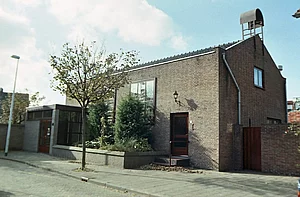 Op de foto is een kerk te zien. Verder staan er een lantaarnpaal en een boom op.
