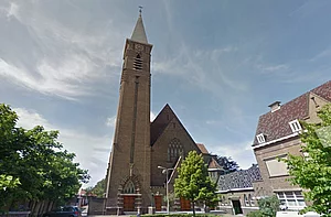 Op de foto zijn een boom, een kerk en een huis te zien