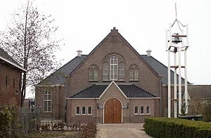 Op de foto zijn een boom, een kerk en een witte klok te zien.
