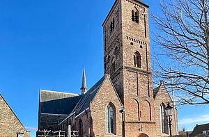 Op de foto is een kerk te zien met daarvoor takken van een boom.